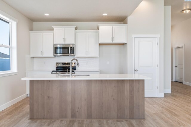 8801 Dusty Maiden Dr, Pasco, WA 99301 - kitchen featuring appliances with stainless steel finishes, a kitchen island with sink, light wood-style flooring, white cabinets, and recessed lighting