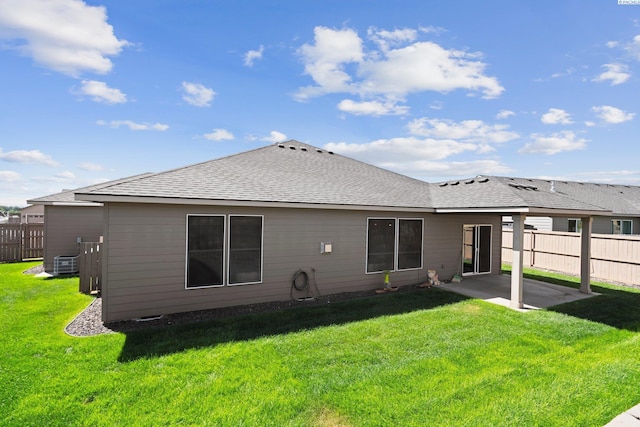 rear view of house with central AC, a patio, and a lawn