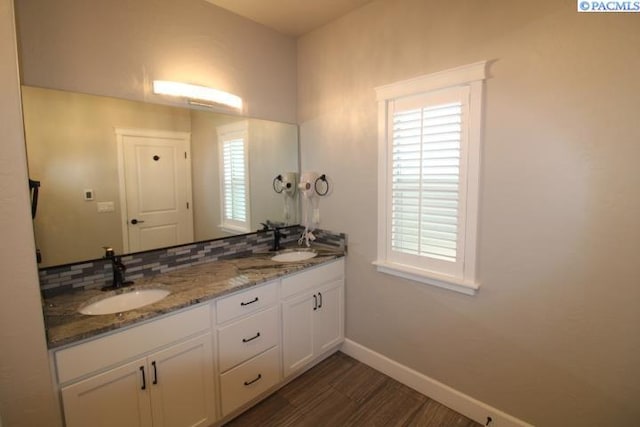 bathroom featuring double vanity, tasteful backsplash, baseboards, and a sink