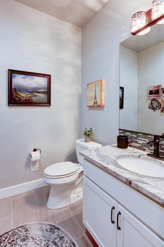 half bathroom featuring vanity, toilet, and baseboards