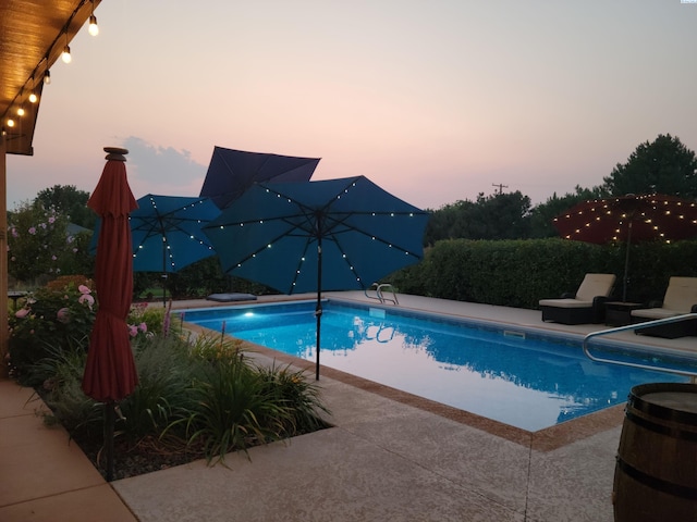 pool at dusk featuring a patio area and an outdoor pool