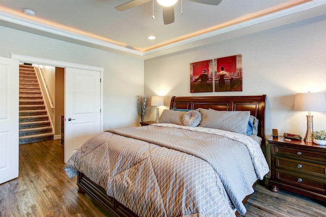 bedroom with a ceiling fan, a tray ceiling, recessed lighting, and wood finished floors