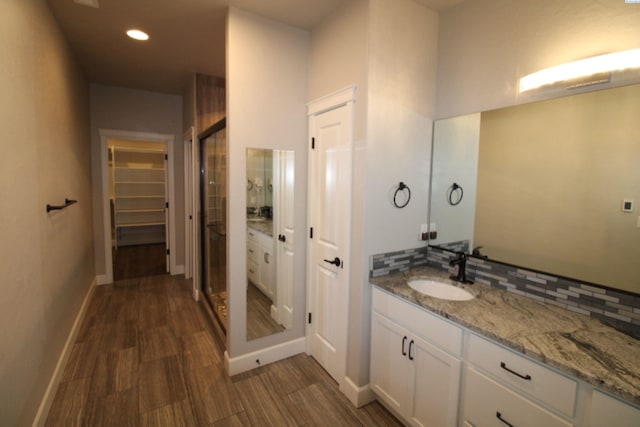 bathroom with baseboards, decorative backsplash, wood finished floors, and vanity