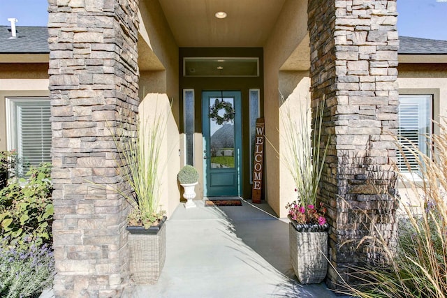 view of exterior entry featuring a shingled roof and stucco siding