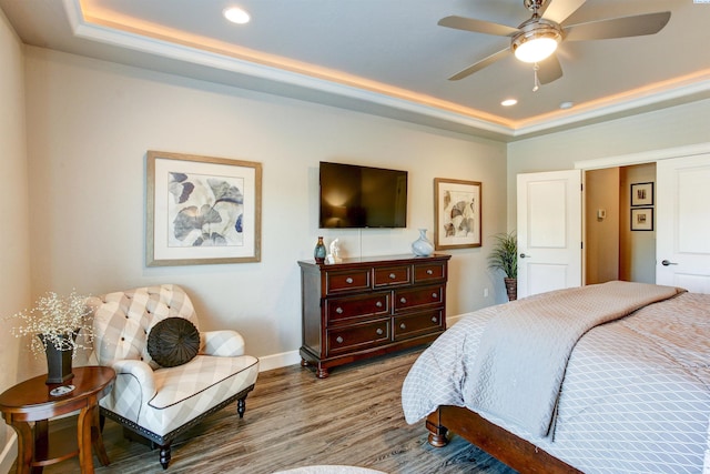 bedroom featuring a tray ceiling, wood finished floors, and recessed lighting