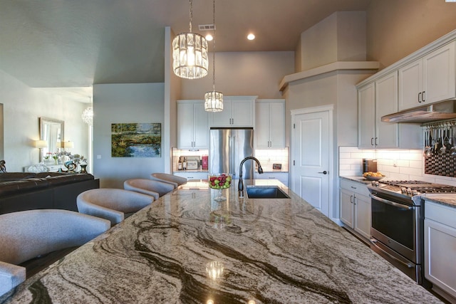 kitchen with open floor plan, stainless steel appliances, a sink, and light stone countertops