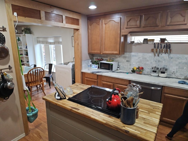 kitchen featuring butcher block counters, light wood-type flooring, decorative backsplash, dishwasher, and brown cabinetry