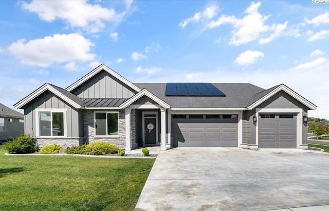 view of front of house with a garage, board and batten siding, a front yard, solar panels, and concrete driveway