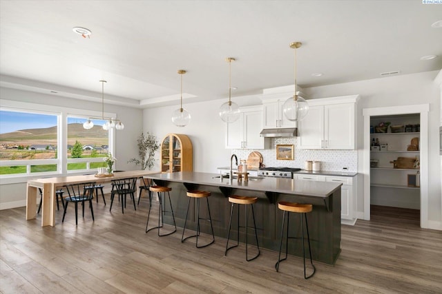 2237 Legacy Ln, Richland, WA 99352 - kitchen featuring a breakfast bar, backsplash, wood finished floors, and an island with sink