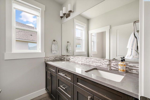 bathroom featuring decorative backsplash, double vanity, baseboards, and wood finished floors