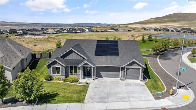 2237 Legacy Ln, Richland, WA 99352 - view of front facade featuring board and batten siding, a garage, concrete driveway, solar panels, and a front lawn