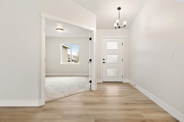 foyer entrance featuring light wood-style flooring, baseboards, and an inviting chandelier