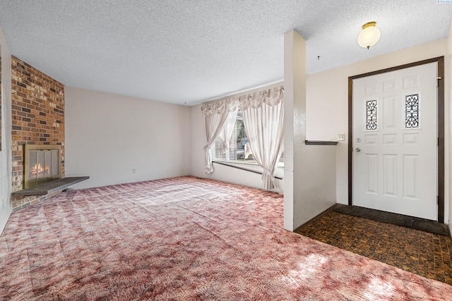 carpeted foyer with a fireplace and a textured ceiling