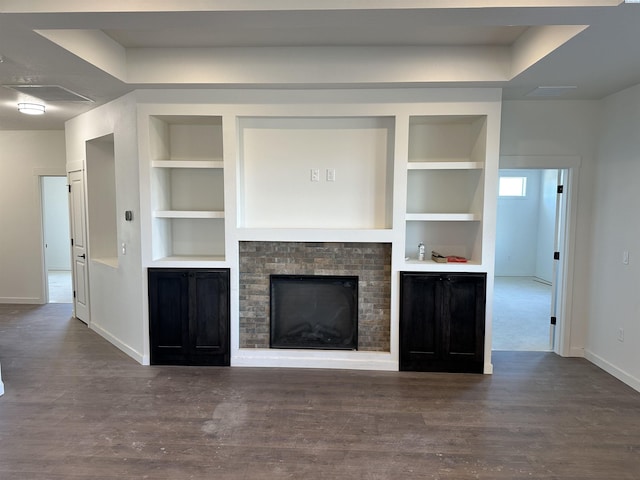 unfurnished living room with baseboards, a fireplace, built in features, and wood finished floors