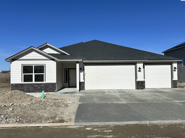 view of front of property featuring stone siding, roof with shingles, driveway, and an attached garage