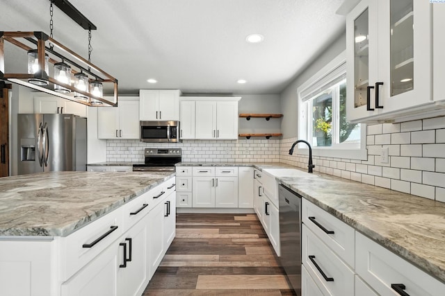 10401 N Mcdonald Rd, Prosser, WA 99350 - kitchen with stainless steel appliances, light stone countertops, dark wood-style flooring, glass insert cabinets, and white cabinetry