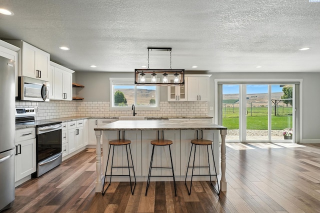 10401 N Mcdonald Rd, Prosser, WA 99350 - kitchen with stainless steel appliances, a kitchen island, open shelves, a breakfast bar, and backsplash