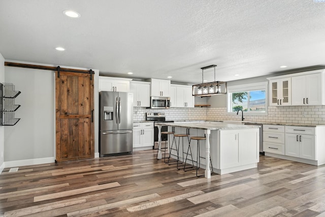 10401 N Mcdonald Rd, Prosser, WA 99350 - kitchen with stainless steel appliances, wood finished floors, backsplash, a kitchen breakfast bar, and white cabinetry