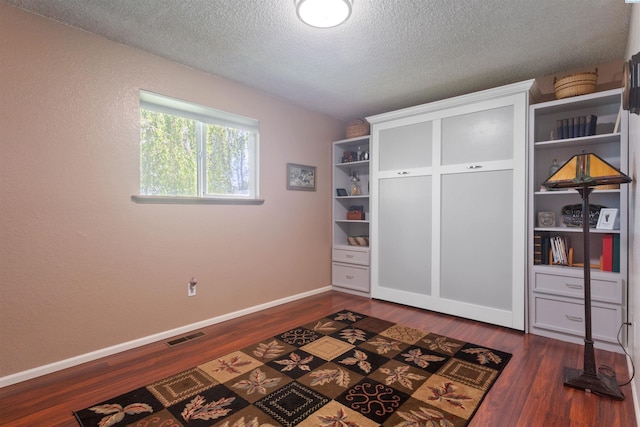 mudroom with dark wood-style flooring, a textured ceiling, and baseboards