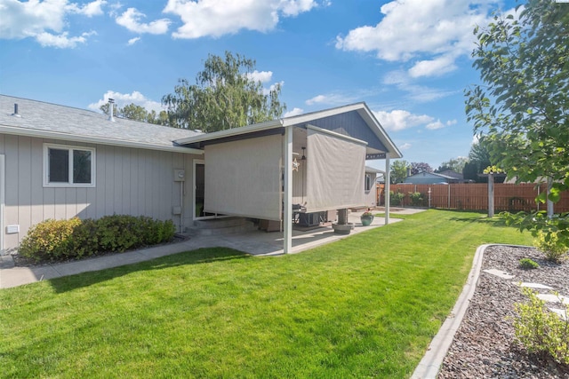 back of property featuring fence, a lawn, and a patio area