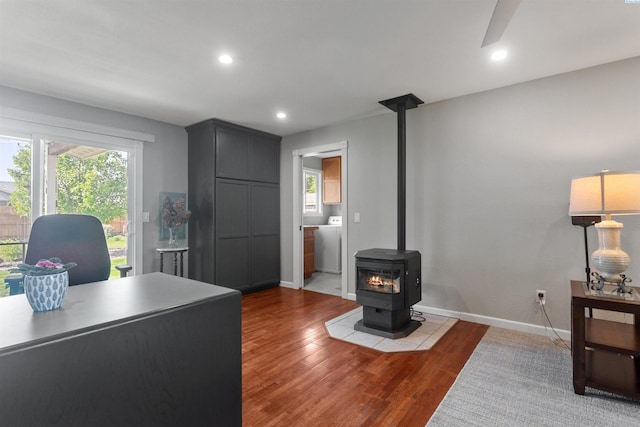 home office featuring baseboards, a wood stove, wood finished floors, and recessed lighting