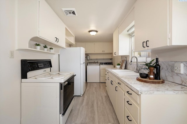 kitchen with white appliances, washer and clothes dryer, open shelves, a sink, and light wood-type flooring