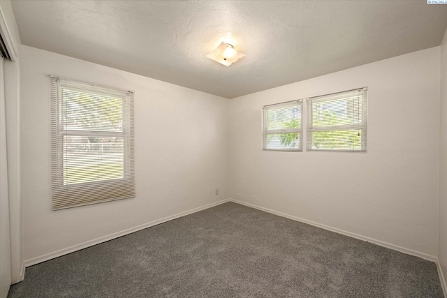 unfurnished room with dark colored carpet and baseboards