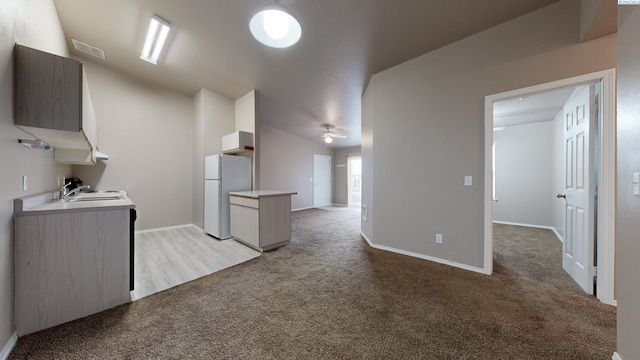 kitchen with white refrigerator, light colored carpet, ceiling fan, and sink