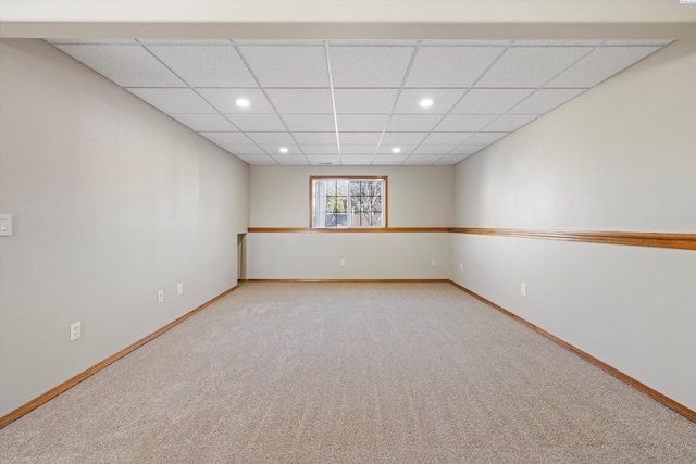 empty room with a drop ceiling, recessed lighting, light colored carpet, and baseboards