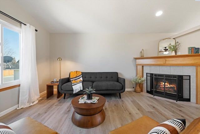 living area featuring baseboards, a tiled fireplace, and wood finished floors