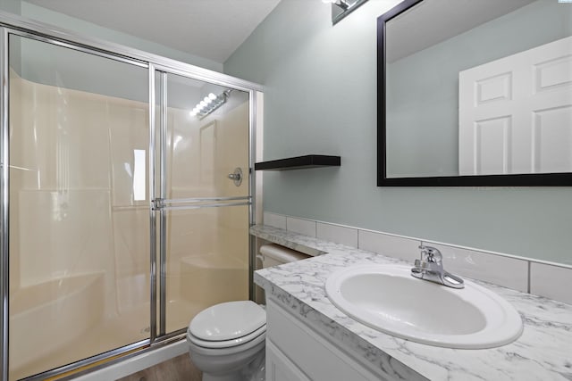 bathroom with vanity, a shower stall, and toilet