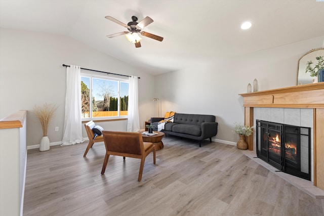 living room with lofted ceiling, light wood finished floors, a fireplace, and baseboards