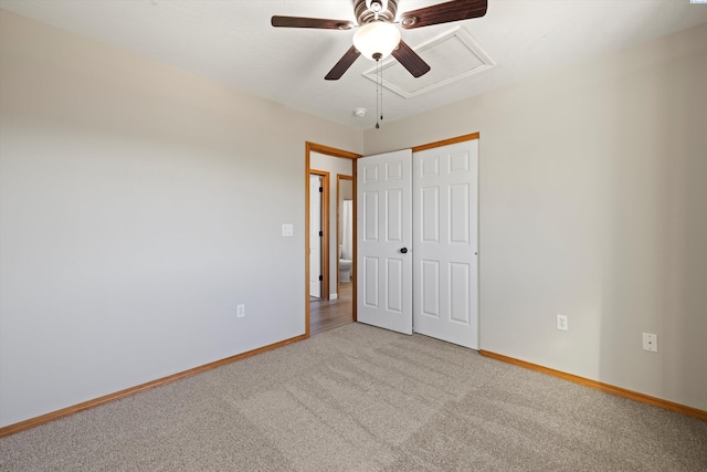 unfurnished bedroom with carpet floors, a closet, attic access, ceiling fan, and baseboards