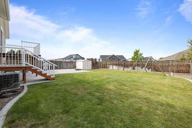 view of yard featuring an outbuilding, a playground, a fenced backyard, a shed, and a patio area