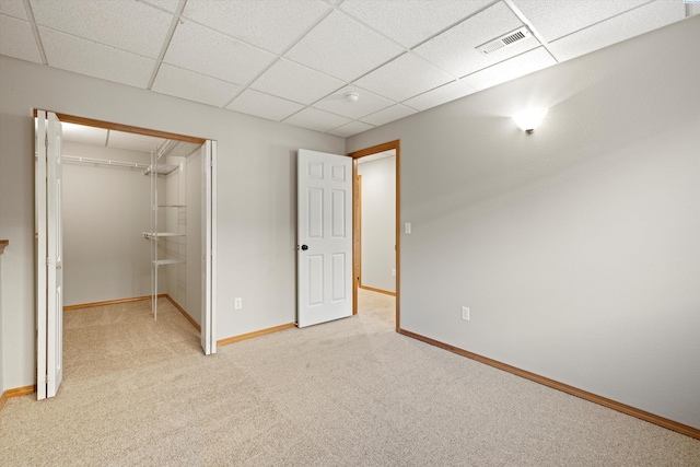 unfurnished bedroom featuring baseboards, visible vents, light colored carpet, a paneled ceiling, and a closet