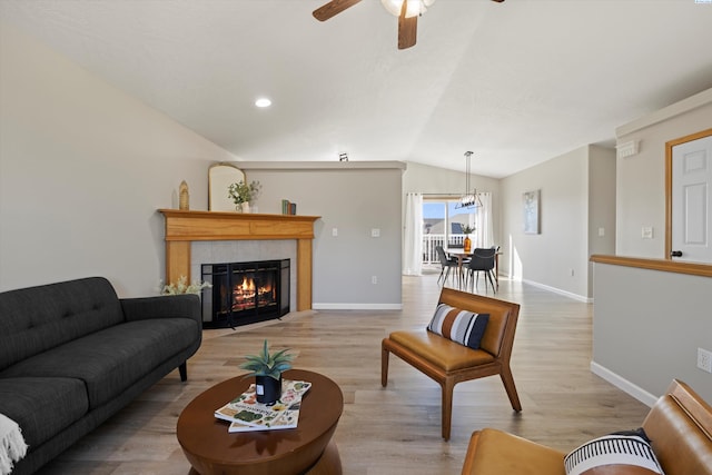 living room with light wood-type flooring, a fireplace, baseboards, and vaulted ceiling