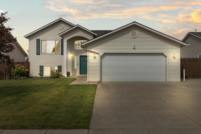 view of front of house with concrete driveway, a lawn, an attached garage, and fence