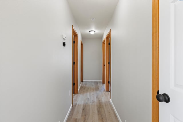 corridor featuring light wood-style flooring and baseboards