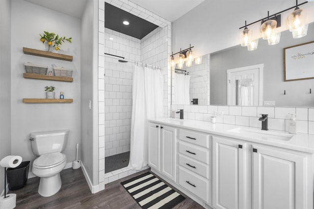 92104 E Sagebrush Rd, Kennewick, WA 99338 - full bathroom with wood finished floors, toilet, a tile shower, double vanity, and backsplash