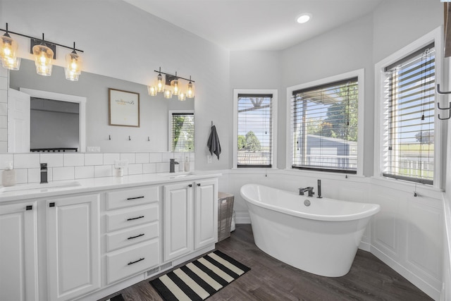 92104 E Sagebrush Rd, Kennewick, WA 99338 - bathroom with double vanity, a soaking tub, wood finished floors, and wainscoting
