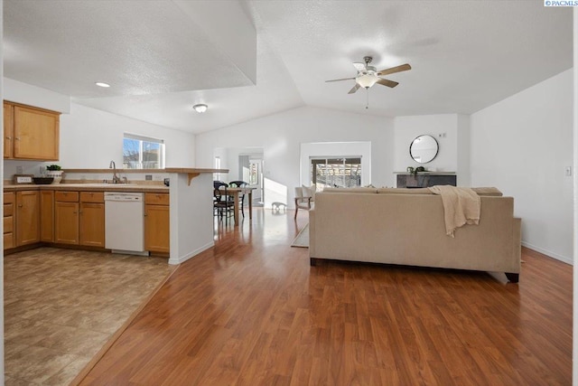 unfurnished living room with lofted ceiling, a textured ceiling, wood finished floors, and a ceiling fan