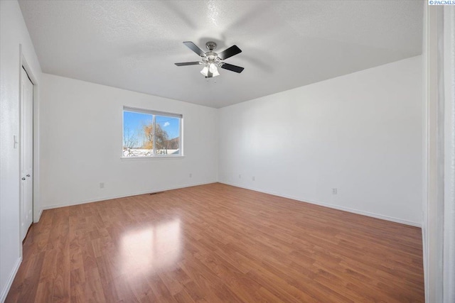 unfurnished bedroom with a textured ceiling, ceiling fan, light wood finished floors, and baseboards