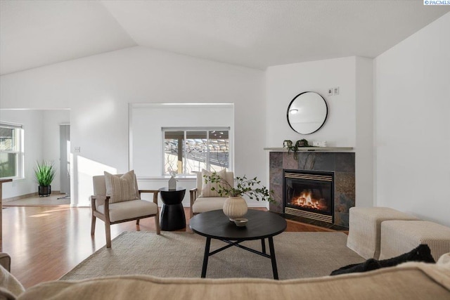 living room with lofted ceiling, a tiled fireplace, and wood finished floors