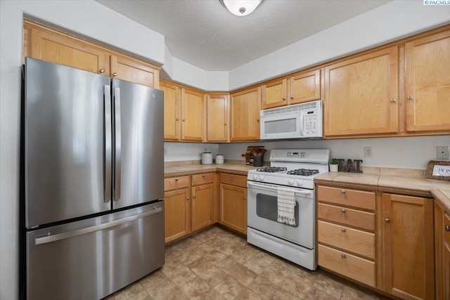 kitchen with tile countertops, white appliances, and a textured ceiling