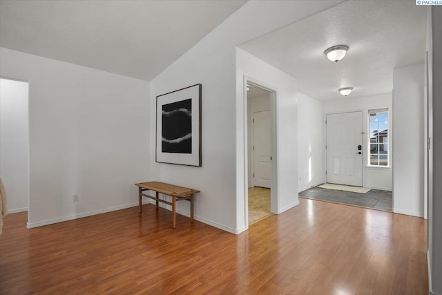 foyer featuring a textured ceiling, baseboards, and wood finished floors