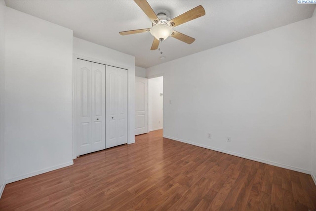 unfurnished bedroom featuring a closet, ceiling fan, baseboards, and wood finished floors