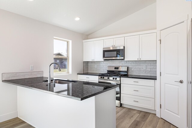 1613 Diamond Ave, Grandview, WA 98930 - kitchen featuring stainless steel appliances, a peninsula, white cabinetry, backsplash, and vaulted ceiling