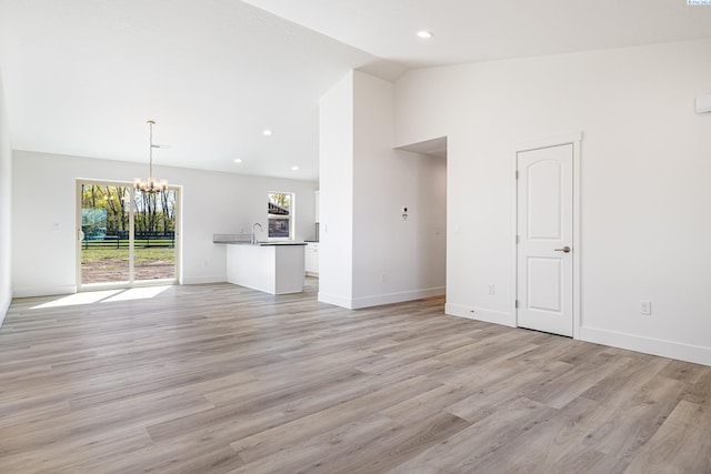 1613 Diamond Ave, Grandview, WA 98930 - unfurnished living room with a chandelier, vaulted ceiling, a sink, light wood-style floors, and baseboards