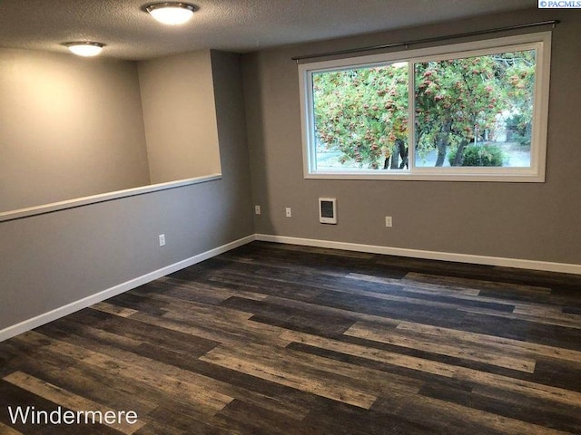 unfurnished room featuring a textured ceiling, dark wood-style flooring, and a healthy amount of sunlight