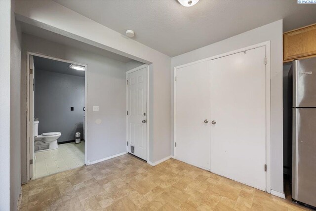 517 S Dawes St, Kennewick, WA 99336 - unfurnished bedroom with freestanding refrigerator, ensuite bath, a closet, and baseboards